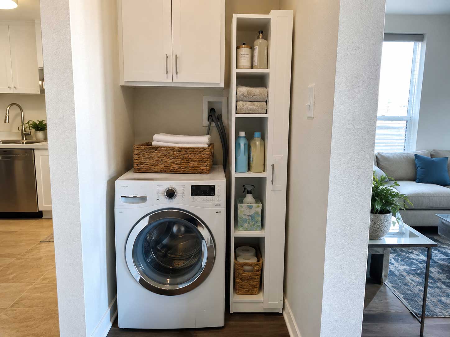 Narrow laundry storage cabinet beside a washer in a small apartment laundry nook.